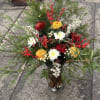 An artistic woodland composition featuring cedar greens, crimson berries, and sculptural blooms