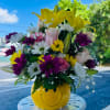 Colorful mixed bouquet in a yellow smiley-face vase outdoors