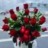 Bouquet of red roses with a red ribbon in a white vase