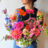 Woman holding a large mixed bouquet in a white vase