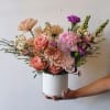 An abundant, garden-style arrangement designed with lush layers of soft spring blooms