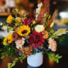 Mixed bouquet of sunflowers, chrysanthemums, and carnations in a white vase