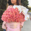 Woman holding a large pink rose box with white orchids