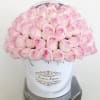 A bouquet of pale pink roses in a white hatbox.