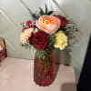 Mixed bouquet of roses and carnations in a red glass vase