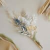 Small dried bouquet with white and blue accents on a neutral background