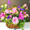 Basket arrangement of pink roses, chrysanthemums, and mixed blooms