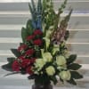 A ONE SIDED ARRANGEMENT CONSISTING OF WHITE ROSES, WHITE MINI CALLA LILLIES