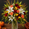 Mixed bouquet of roses, lilies, and calla lilies in a glass vase