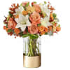 Peach roses and white lilies in a glass vase with a gold wrap