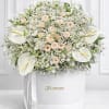 White floral arrangement with roses and calla lilies in a round box