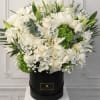 White floral arrangement in a black hat box with green accents