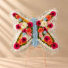 Butterfly-shaped floral arrangement on a wooden easel with pink, orange, blue, and white flowers
