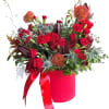 Red floral arrangement in a pink hatbox with ribbon