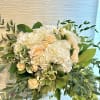 White hydrangeas and peach roses in a lush bouquet with greenery