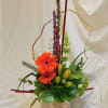 Orange gerbera daisies in a wooden box with purple spikes and green buds