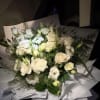 Bouquet of white roses and white lisianthus wrapped in white paper
