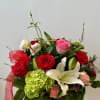 A romantic garden-style basket featuring vibrant roses, elegant lilies, and soft seasonal