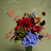 Red and blue floral arrangement in a clear glass vase with a bronze heart accent