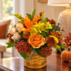Autumn flower arrangement in a woven basket with orange and yellow blooms