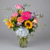 Colorful mixed bouquet in a clear glass vase with lilies, roses, gerbera daisies, and hydrangeas