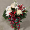 White roses and daisies in a glass vase with red berries and a festive ribbon