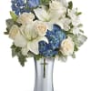 White lilies and roses with blue hydrangeas in a silver vase