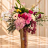 Mixed pink and white floral arrangement in a gold vase