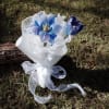 Small bouquet of blue flowers wrapped in white paper with a sheer ribbon