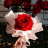 A timeless gesture wrapped in elegance. This single red rose, cradled in