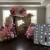 Pink and white balloon arch with a lit "16" sign and gold backdrop