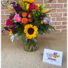 Colorful mixed bouquet in a clear glass vase with sunflowers and roses