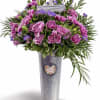 Purple carnations and daisies in a tall silver vase