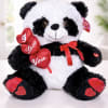 Plush panda bear holding red heart decorations and a ribbon