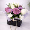 Pink and white roses with small daisies in a black gift box