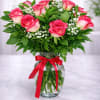 Pink roses in a glass vase with a red ribbon
