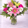 Pink lilies and roses arranged in a clear glass vase