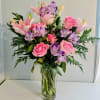 Blush roses and pale pink lilies mingle with purple alstroemeria in a