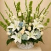 A graceful standing basket featuring elegant white lilies, ivory roses, soft blue