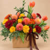 Mixed bouquet of chrysanthemums and tulips in a brown gift bag with ribbon