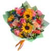 Mixed bouquet with sunflowers, pink roses, and coral blooms wrapped in green paper