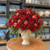 Red roses and apples arranged in a cream vase