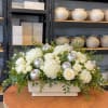 White roses and hydrangeas in a rectangular vase with silver apple accents