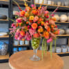 Colorful flower arrangement in a clear glass vase filled with green apples