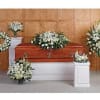 White funeral floral arrangements around a wooden casket