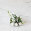 A delicate and elegant floral centerpiece designed with soft white blooms and