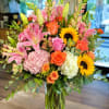 A bright, abundant statement in warm tones, this large mixed flower arrangement
