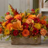 A dense, low centerpiece that bursts with warm autumn color-this flower arrangement