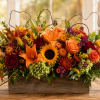 Autumn floral arrangement in a wooden box with lilies, roses, sunflowers, and mums