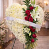A large heart-shaped standing spray of white chrysanthemums offers a quiet, heartfelt